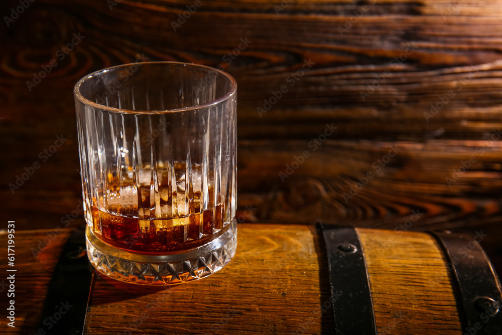 Barrel with glass of cold rum on wooden background