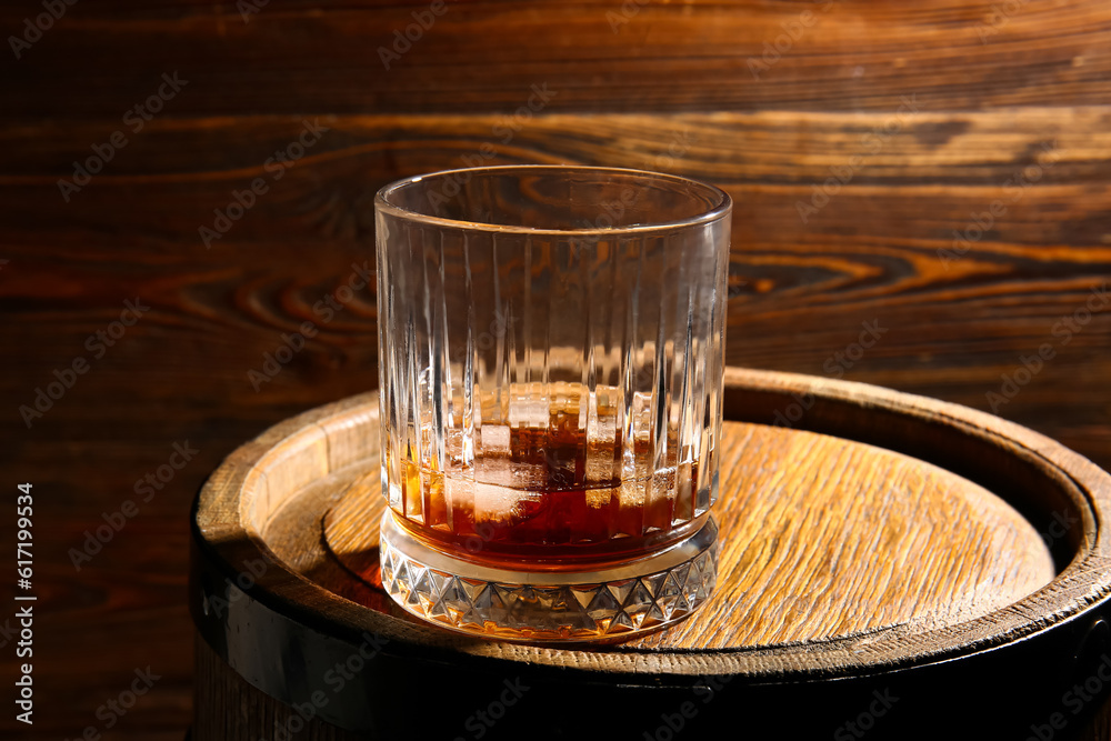 Barrel with glass of cold rum on wooden background