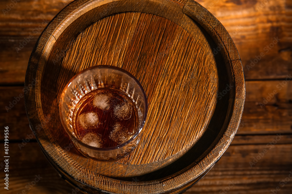 Barrel with glass of cold rum on wooden background