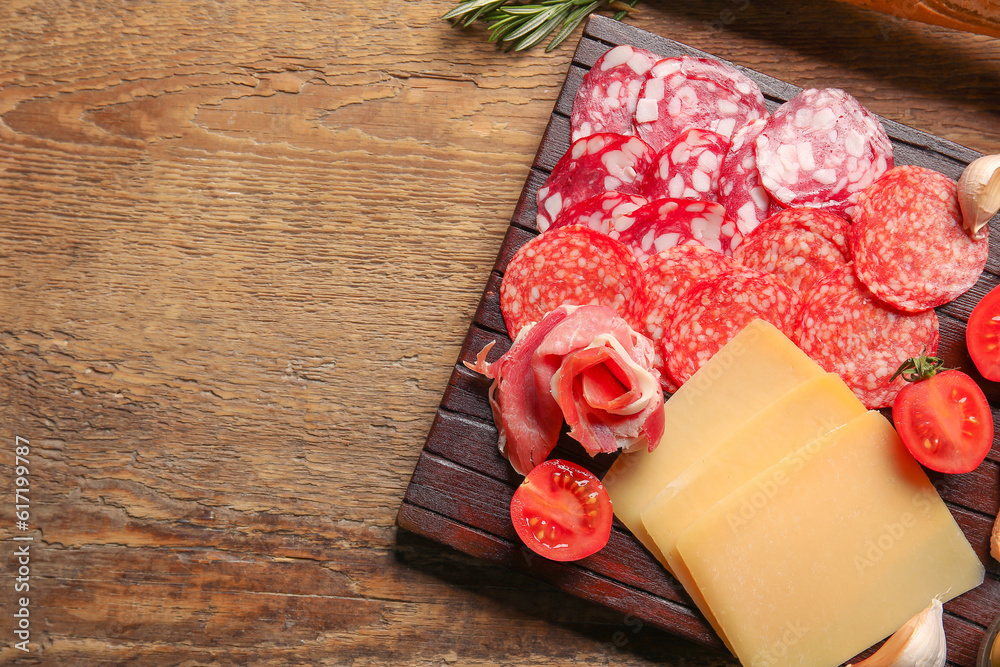 Board with assortment of tasty deli meats and cheese on wooden background