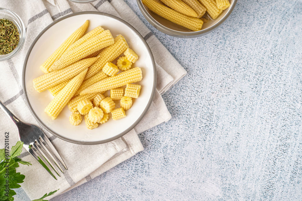 Plate with tasty canned corn cobs on light background