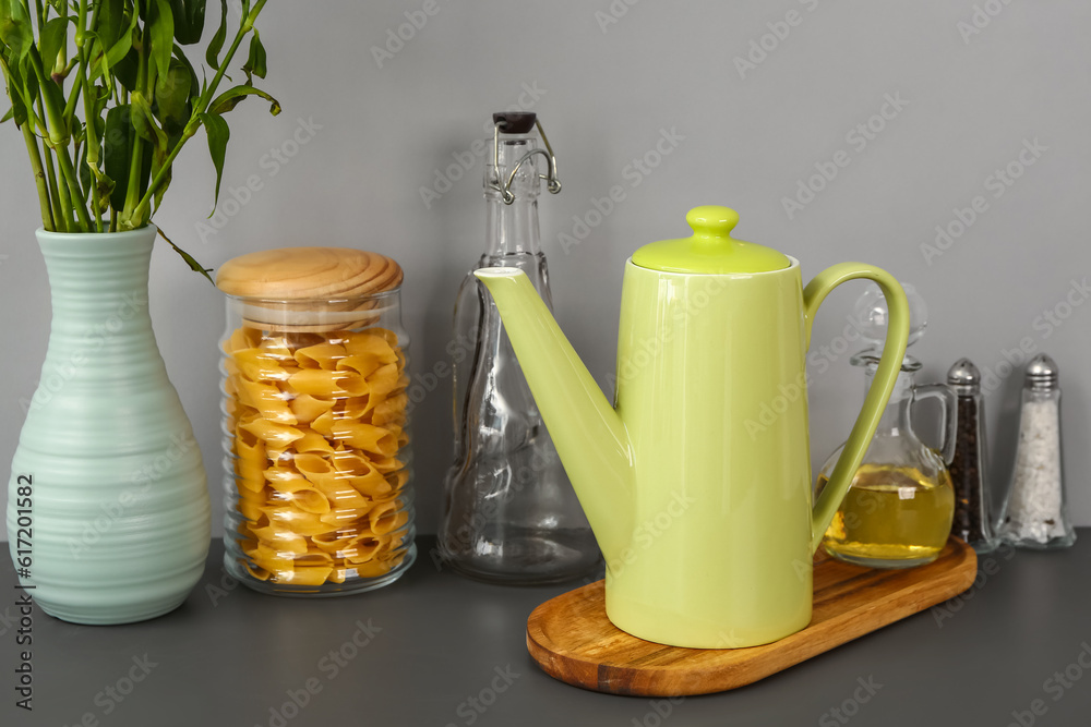 Teapot with flowers and different kitchen stuff on black table