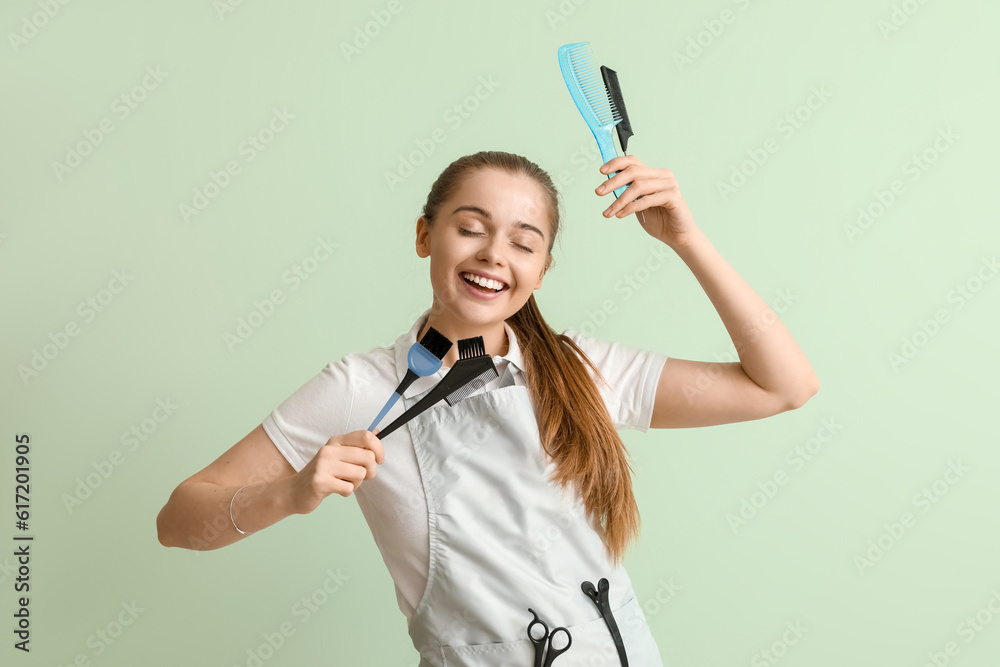 Female hairdresser with brushes on green background