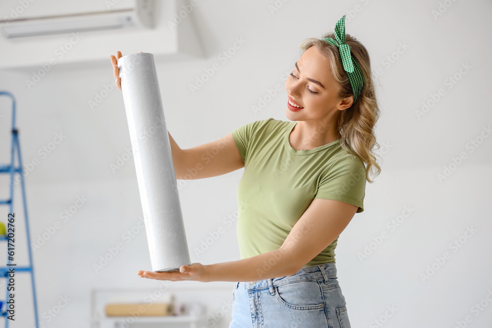 Young woman with wallpaper roll at home