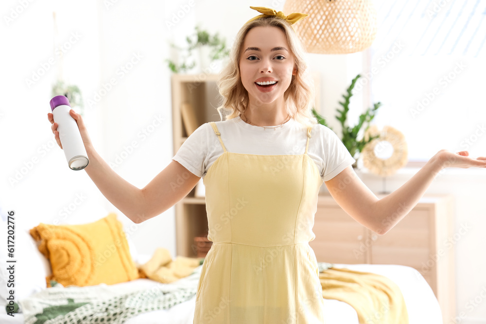 Young woman with air freshener in bedroom