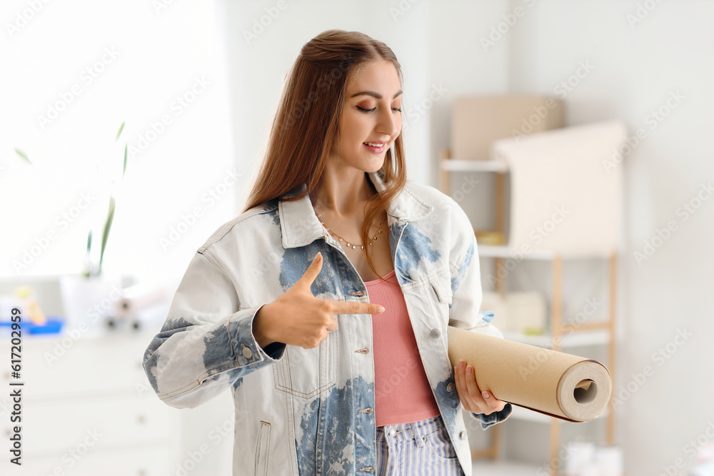 Young woman pointing at wallpaper roll in room