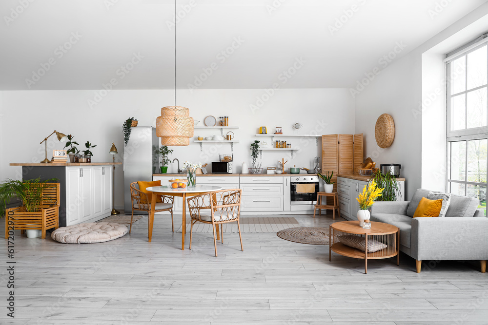 Interior of light kitchen with stylish fridge, counters, sofa and table