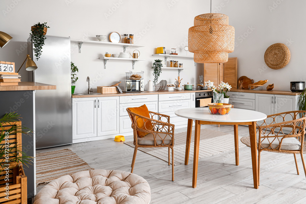 Interior of light kitchen with stylish fridge, counters, shelves, table and chairs