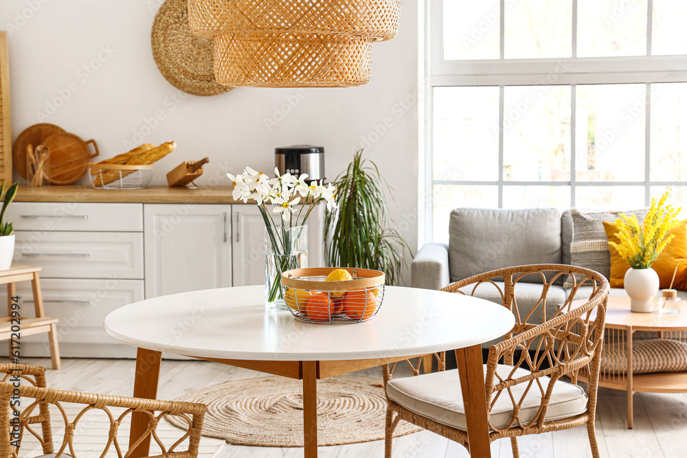 Interior of light kitchen with stylish counters, table, chairs and sofa