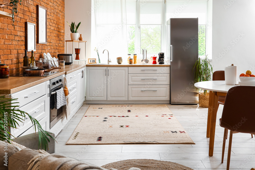 Interior of kitchen with stylish fridge, counters, window and table