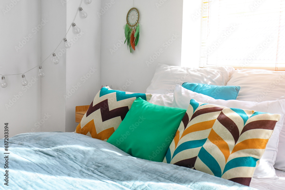 Interior of modern bedroom with bed and dream catcher hanging on white wall