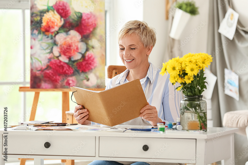 Mature female artist with sketchbook in  workshop