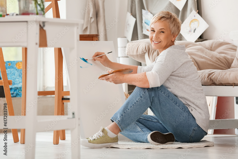 Mature female artist painting picture in  workshop