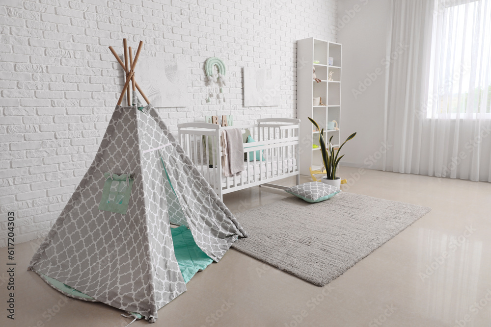 Stylish modern interior of childrens room with baby bed and play tent