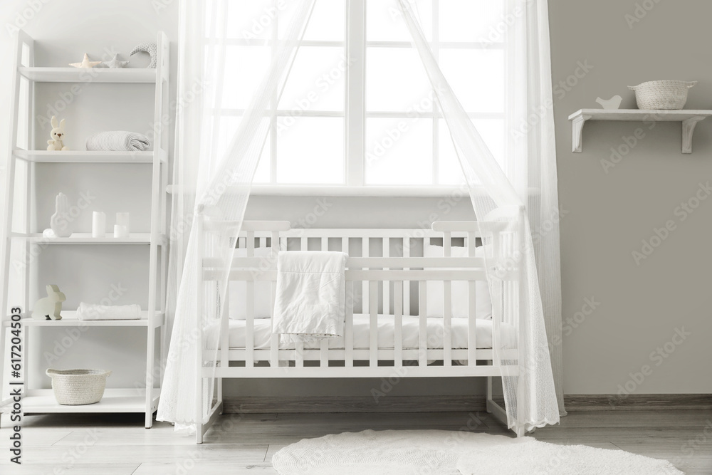 Interior of stylish childrens bedroom with crib and shelving unit