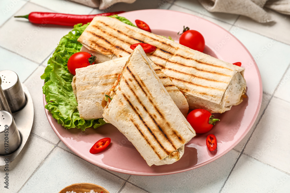 Plate of tasty shawarma with lettuce and tomatoes on white tile table