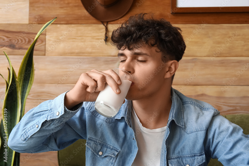 Young man drinking milk at home, closeup