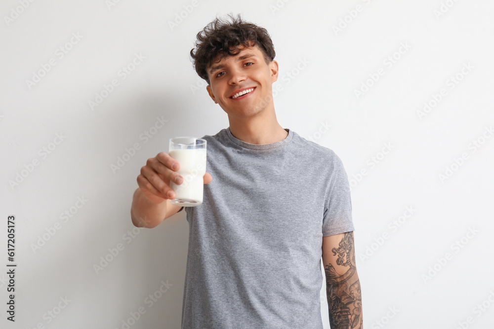 Young man with glass of milk on white background