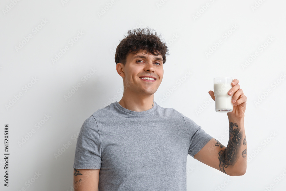 Young man with glass of milk on white background