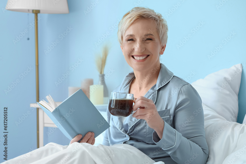 Mature woman with cup of coffee and notebook in bed