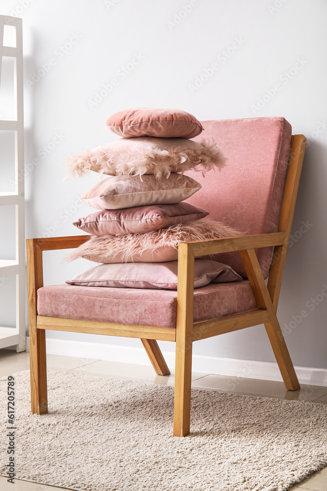 Armchair with cozy pillows near light wall in room