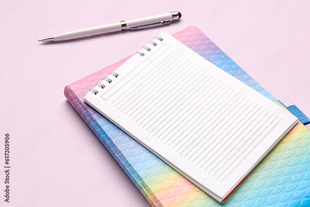 Notebooks with pen on pink background, closeup