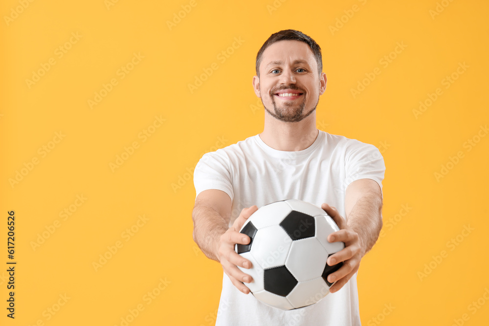 Happy man with soccer ball on yellow background