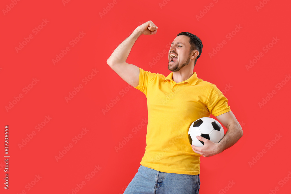 Emotional man with soccer ball on red background