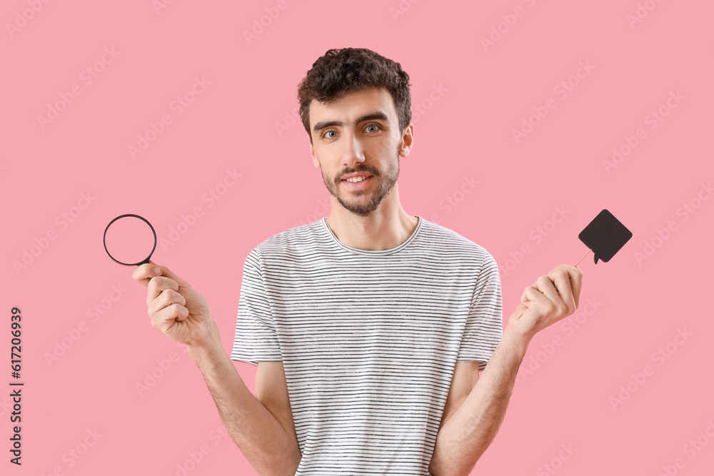 Young man with magnifier and speech bubble on pink background