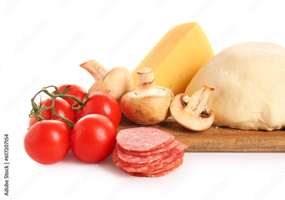 Wooden board with raw dough and ingredients for preparing pizza on white background