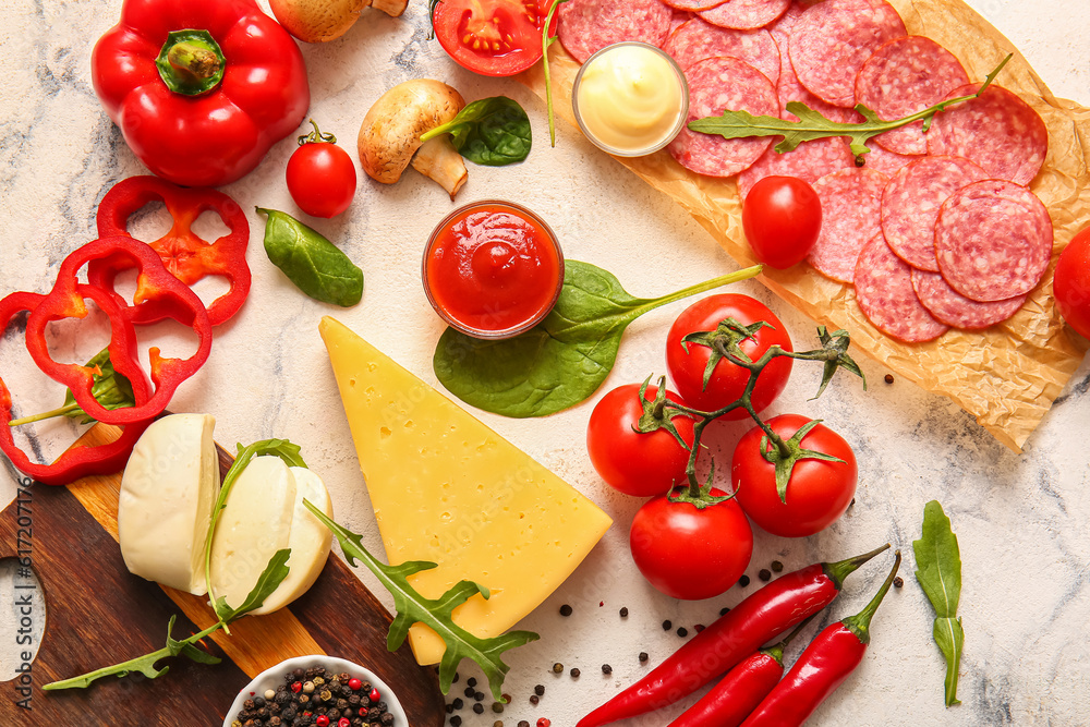 Different ingredients for preparing pizza on white marble background