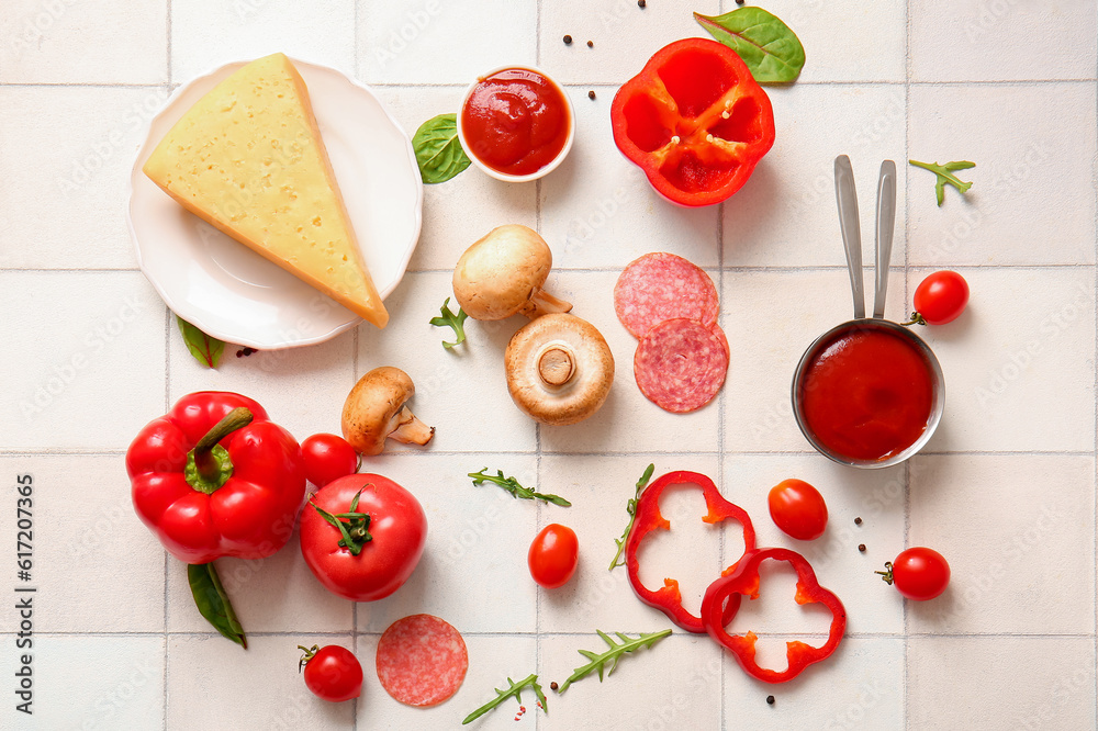 Different ingredients for preparing pizza on white tile background