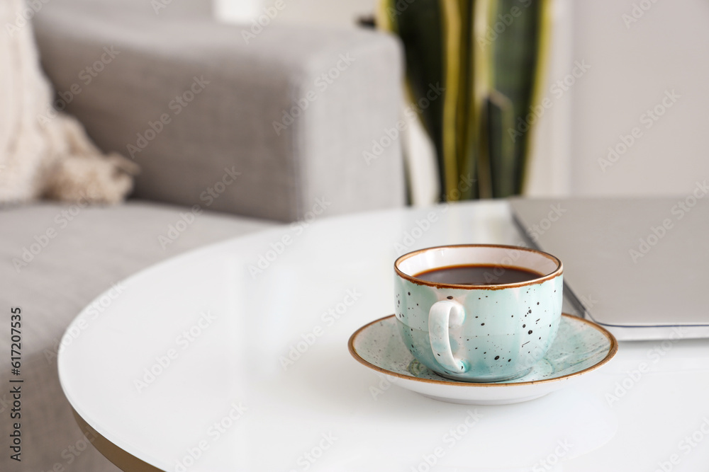 Cup of delicious coffee and modern laptop on table, closeup