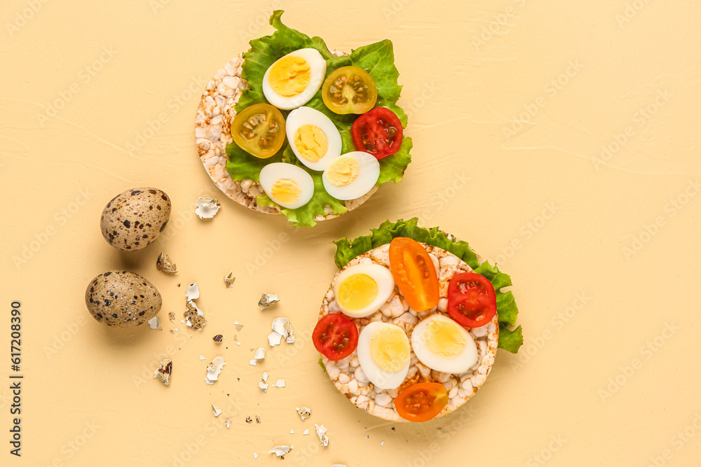 Rice crackers with quail eggs, tomatoes and lettuce on beige background