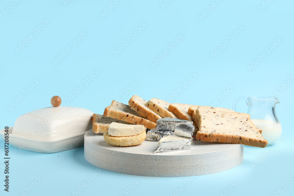 Board with triangles of tasty processed cheese and toasts on blue background