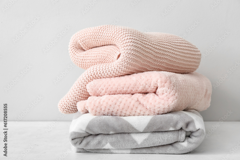 New soft folded blankets on table near light wall