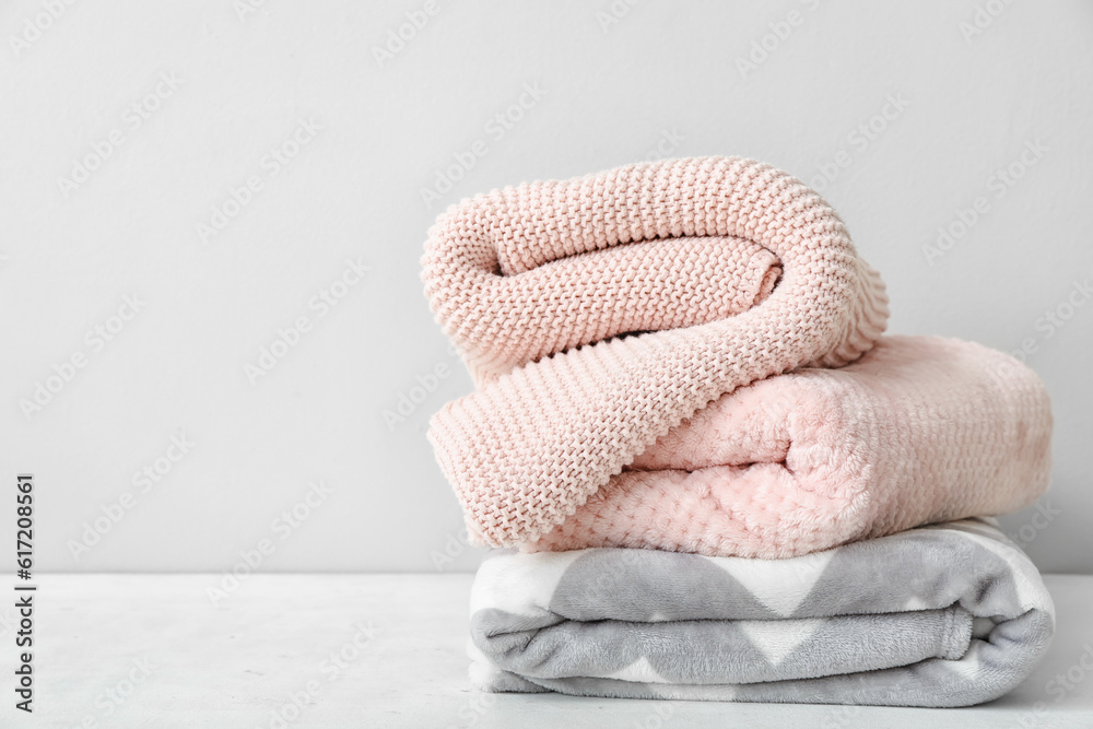 New soft folded blankets on table near light wall