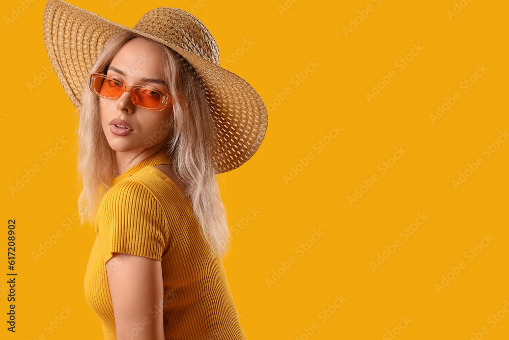 Young woman in stylish sunglasses on orange background