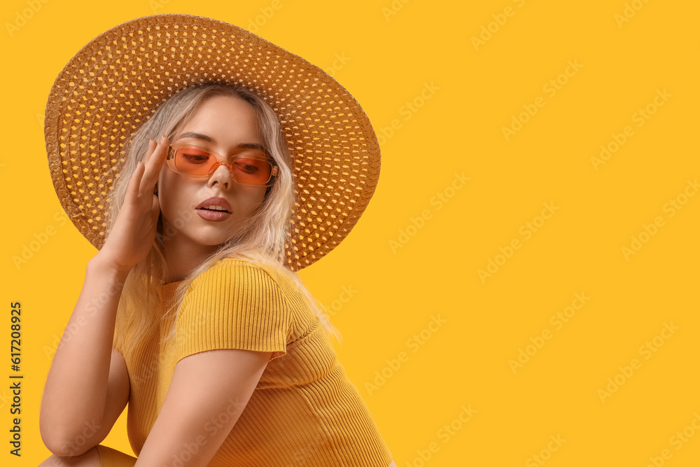 Young woman in stylish sunglasses on orange background