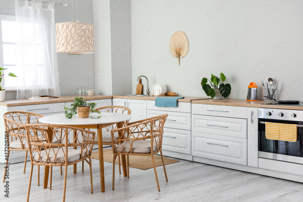 Interior of light kitchen with white counters, electric oven and dining table