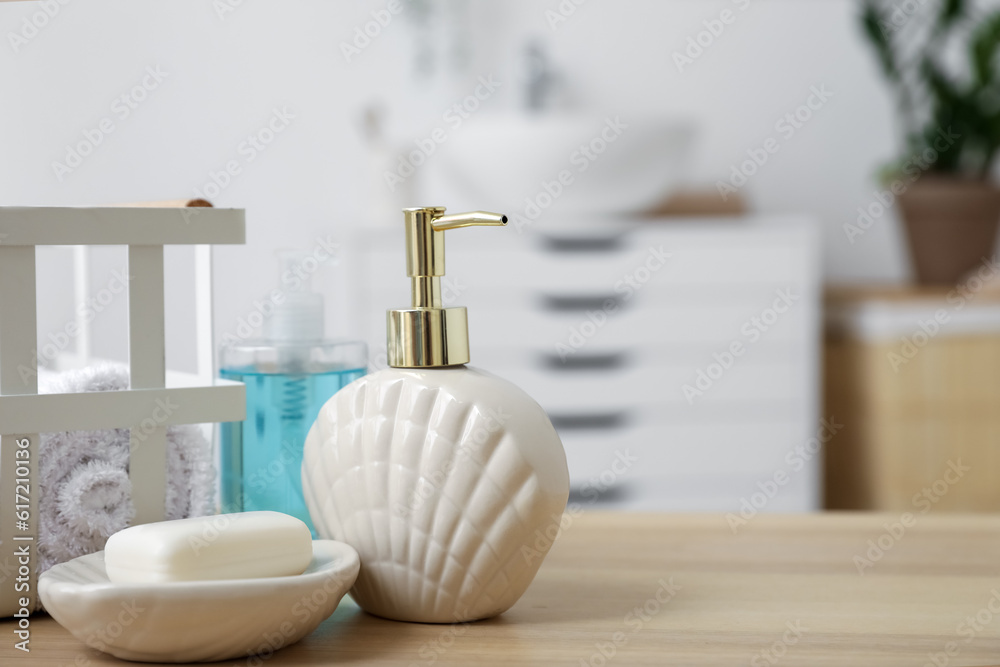 Soap bar and dispenser on wooden table in bathroom, closeup