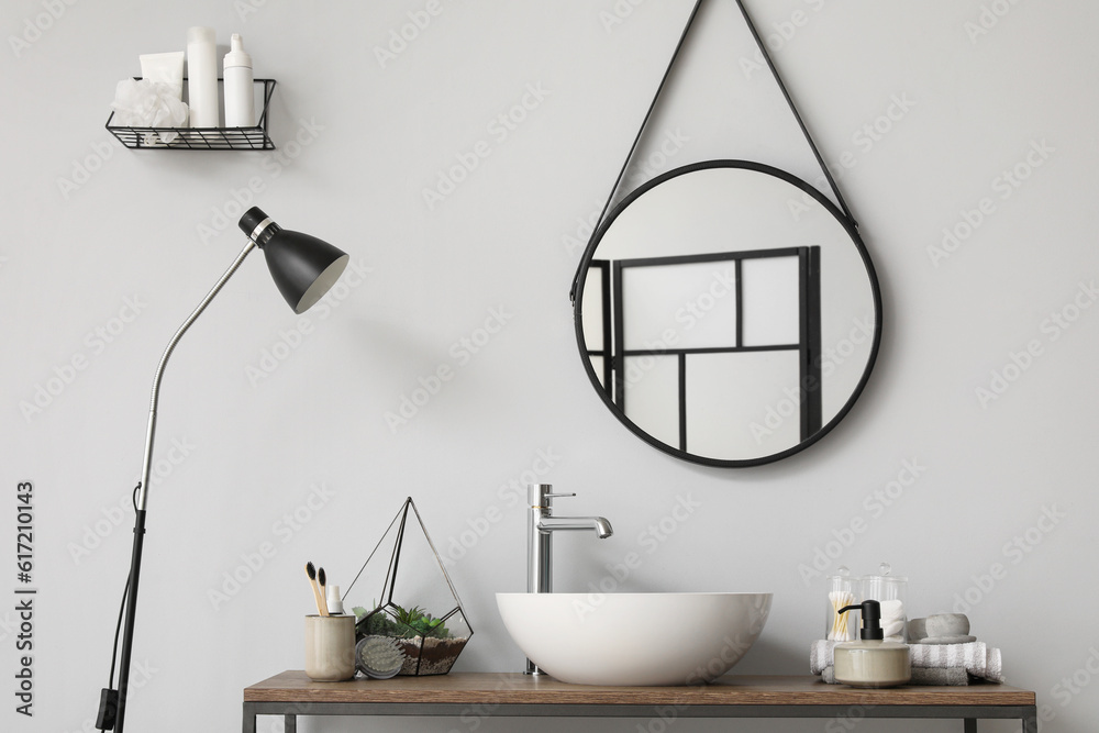 Table with sink bowl, bath accessories and mirror in bathroom