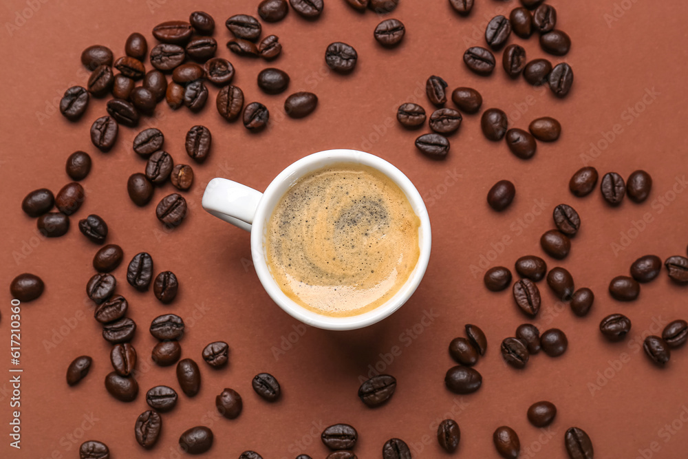 Cup of hot espresso and coffee beans on brown background