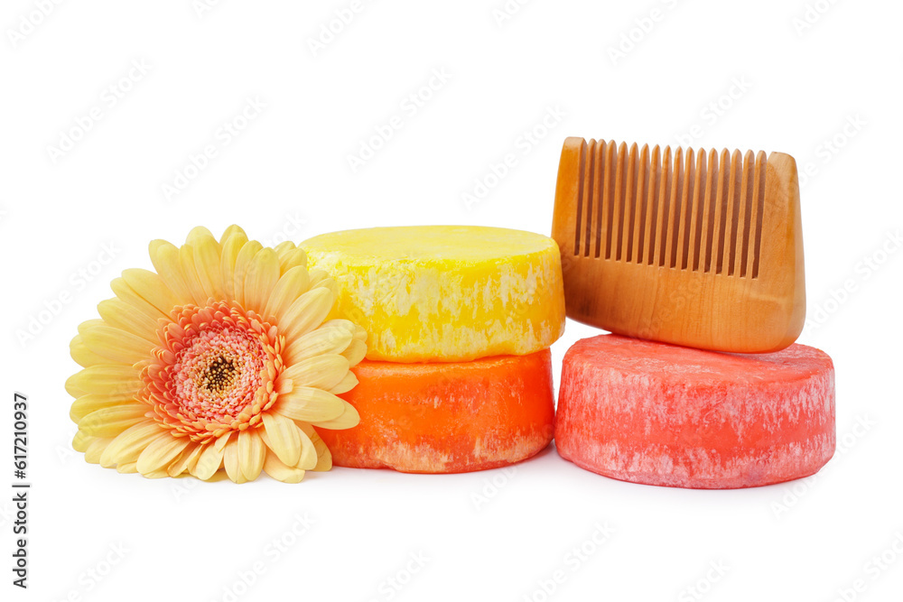 Colorful solid shampoo bars with flower and comb on white background