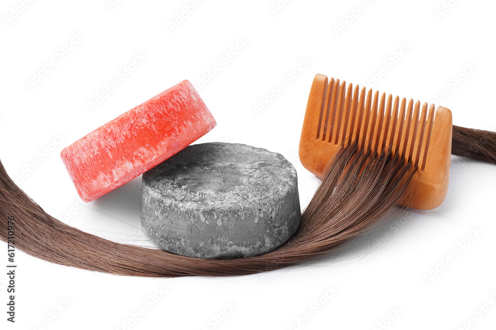 Colorful solid shampoo bars with hair and comb on white background