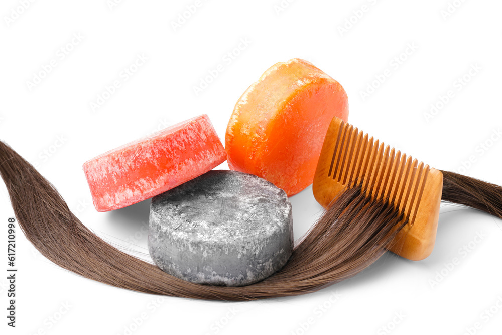 Colorful solid shampoo bars with hair and comb on white background