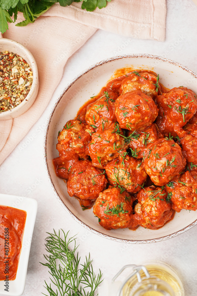 Bowl of tasty meat balls with sauce on light background