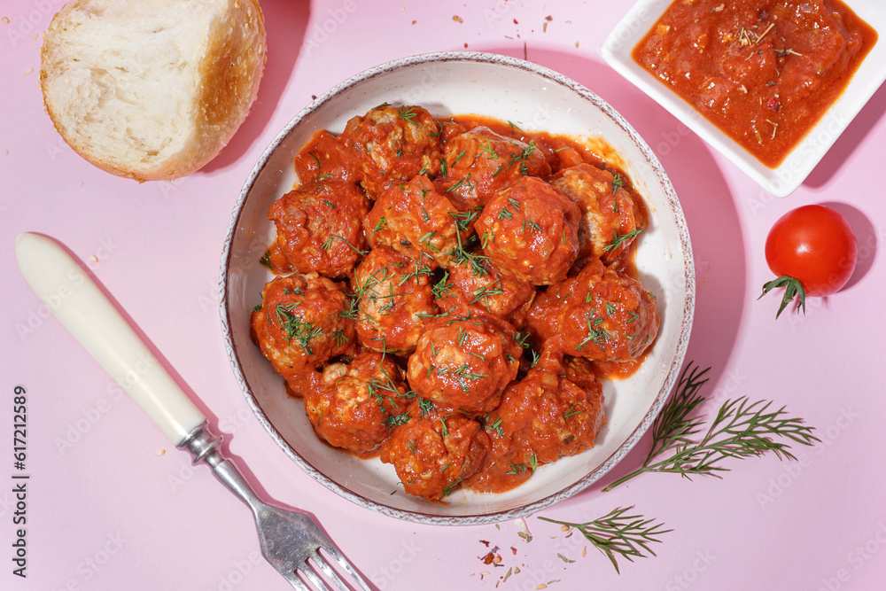 Bowl of tasty meat balls with sauce on pink background