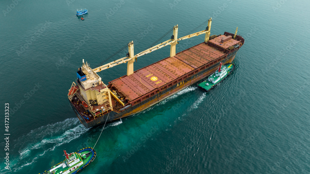 Aerial top view of cargo ship carrying container and running with tug boat for import export goods f