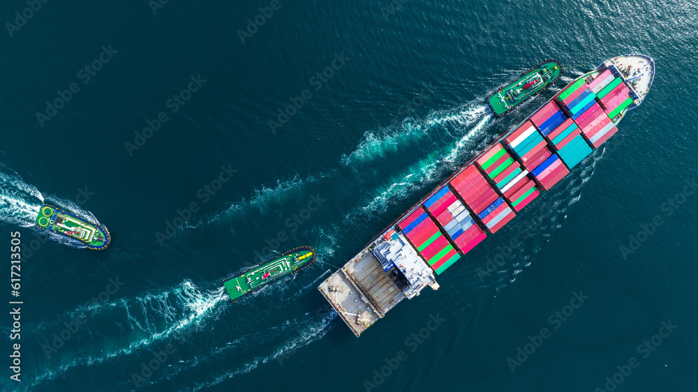 Aerial top view of cargo ship carrying container and running with tug boat for import export goods f